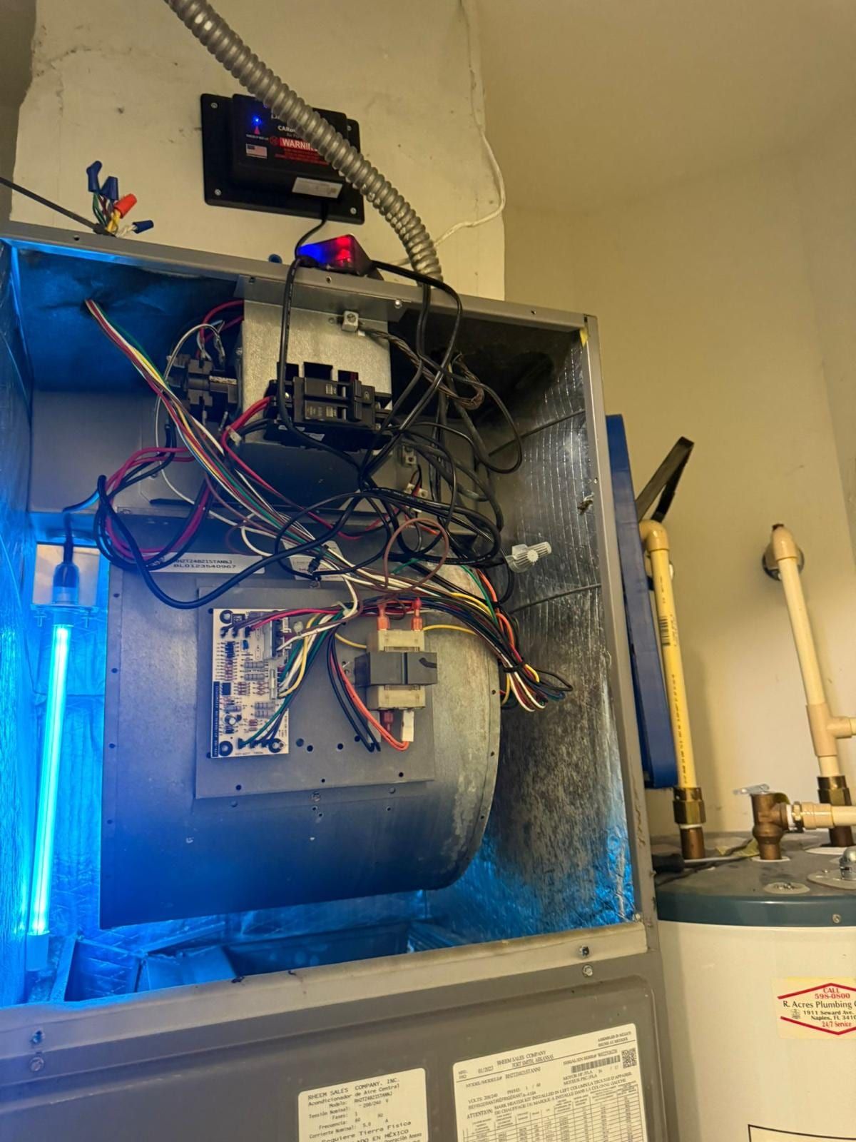 Interior del gabinete de un manejador de aire con una lámpara UV germicida encendida junto a la carcasa del ventilador y el cableado de control