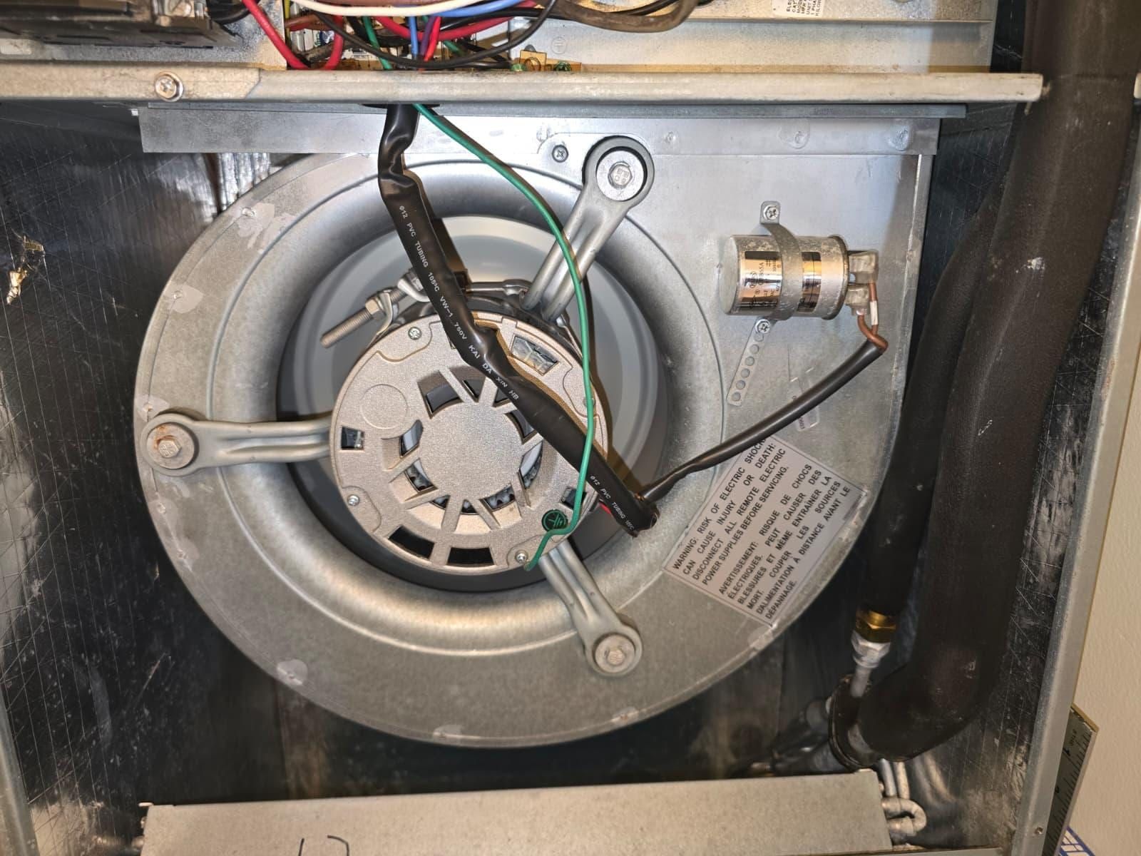 Close view of a blower motor assembly, its capacitor, wiring and bilingual electrical warning label